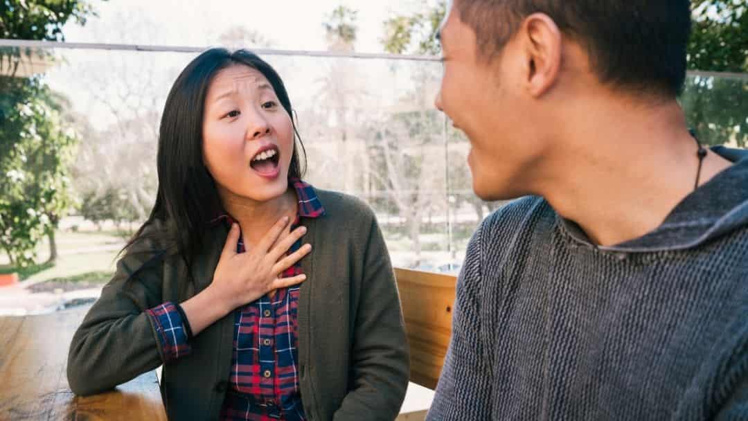 Aasialaistaustaine nainen ja mies keskustelevat puistossa
