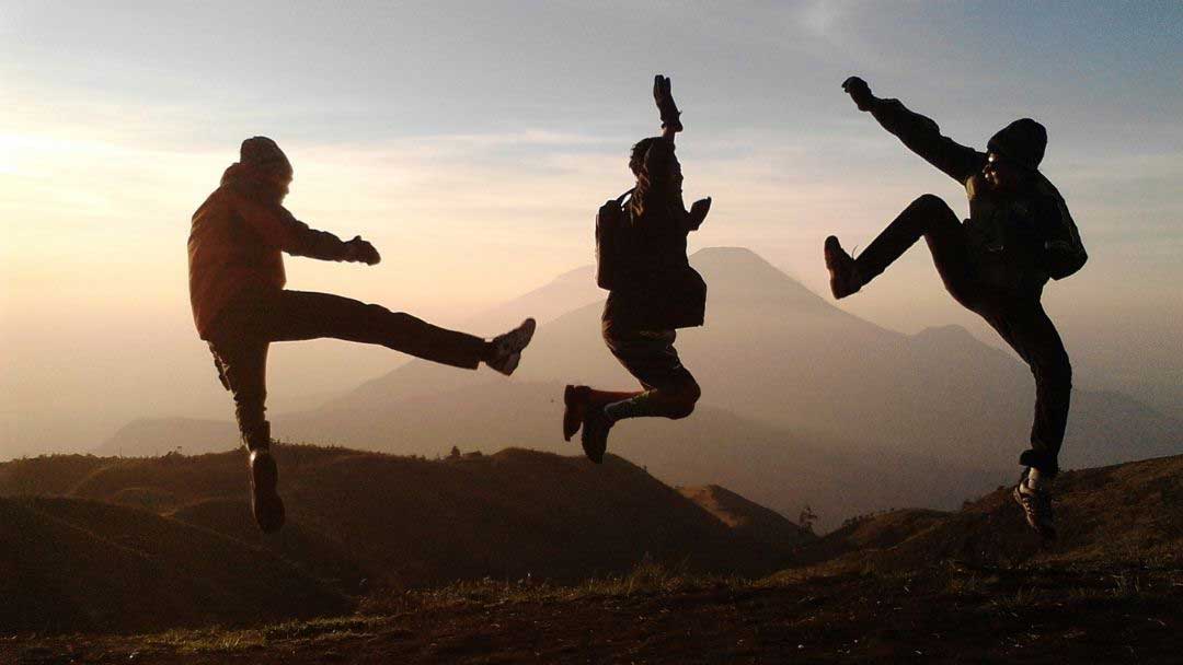 Kolme nuorta hyppäävät ilmaan auringonlaskua vasten, muodostaen silhuettina vartaloillaan kirjaimet KEO